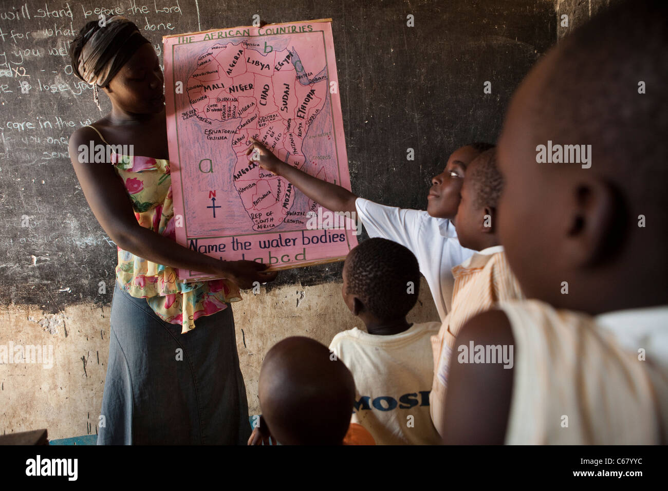 Studenten zeigen auf einer Karte von Afrika in einem Klassenzimmer in Amuria, Uganda, Ostafrika. Stockfoto