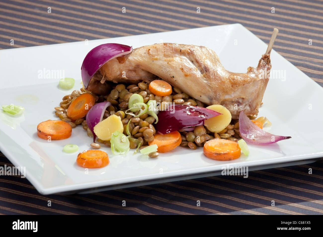 Gebratene Kaninchenkeule mit Linsen und Gemüsebeilage Stockfoto