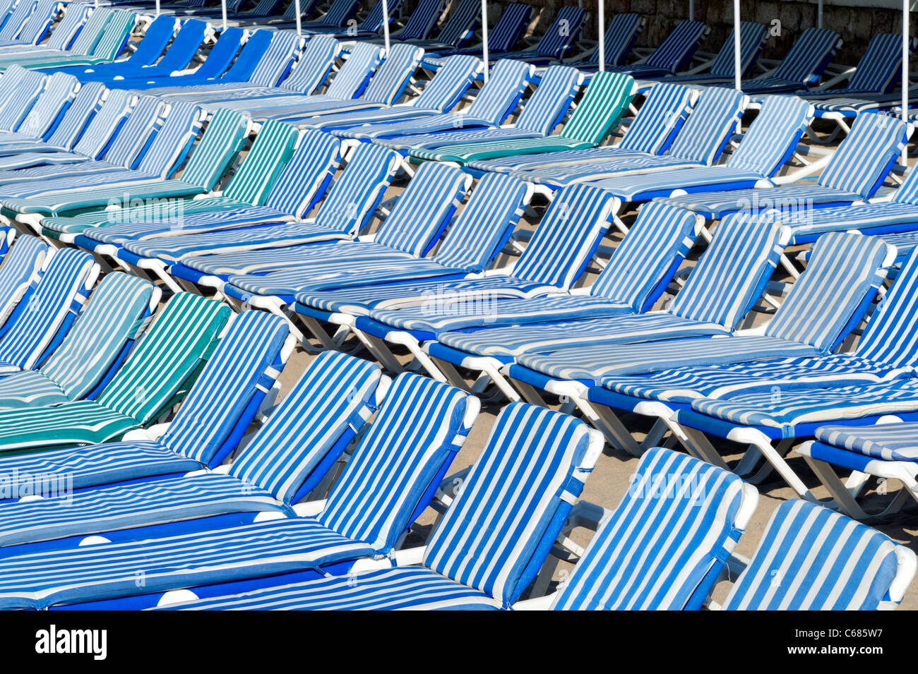 Blau-weiße gestreifte gepolsterte Sonnenliegen am Strand zusammen verpackt Stockfoto