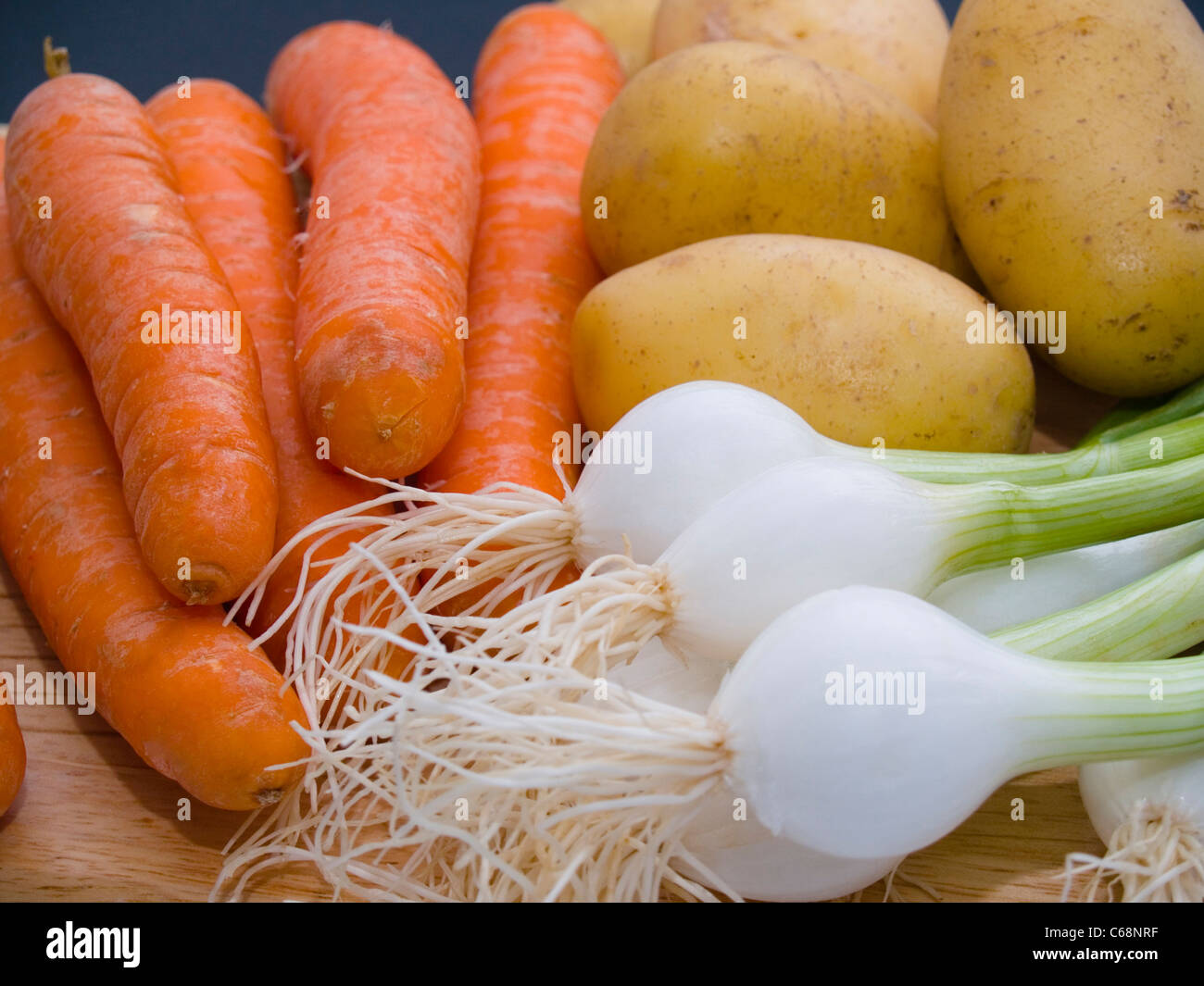 Frühlingszwiebeln, Möhren Und Kartoffeln Auf Einem Schneidbrett | Frühlingszwiebeln, Karotten und Kartoffeln auf ein Schneidebrett Stockfoto