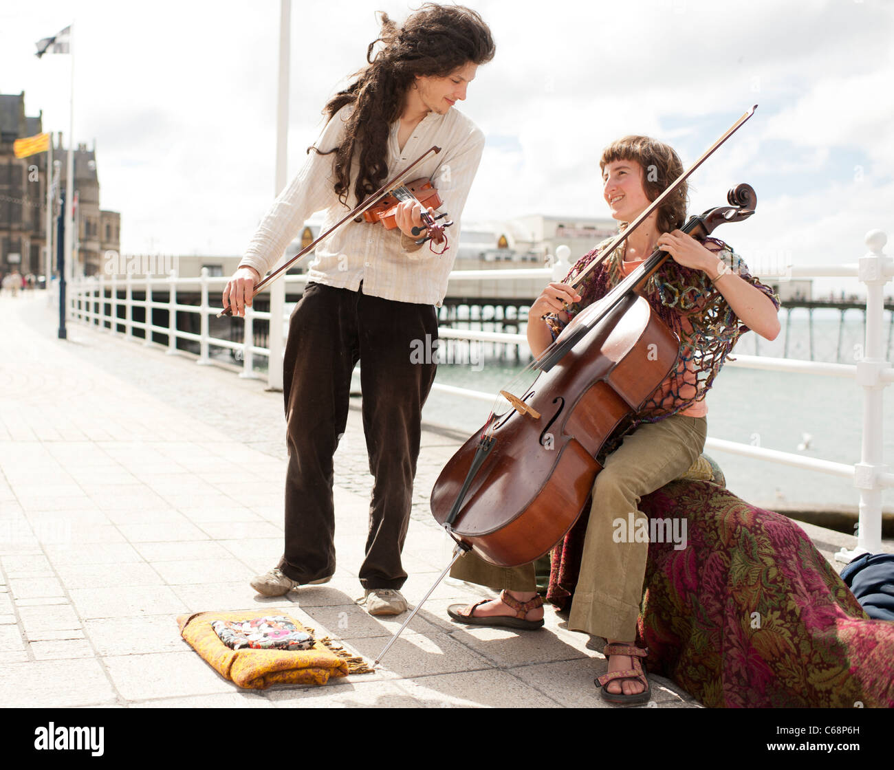 Zwei junge Leute spielen Cello und Violine als Straßenmusikant auf Aberystwyth promenade. Sommernachmittag Wales UK Stockfoto