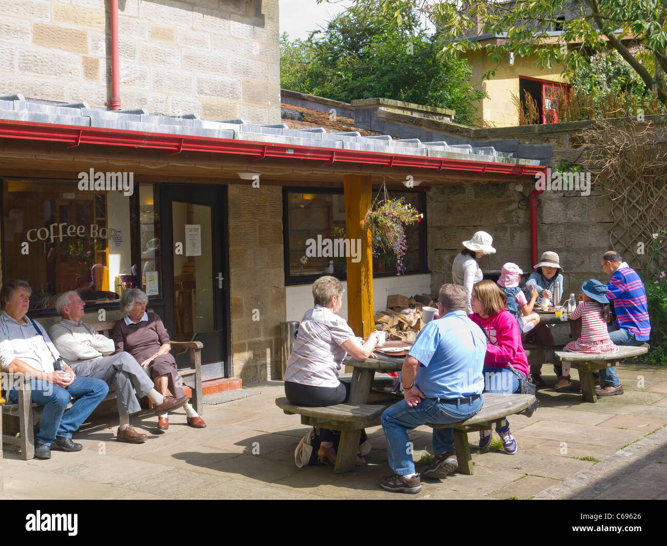 Bewohner und Besucher genießen die Sommersonne an der Kaffeebar in Botton Dorf, ein Camphill Village Vertrauen Heim für Behinderte. Stockfoto