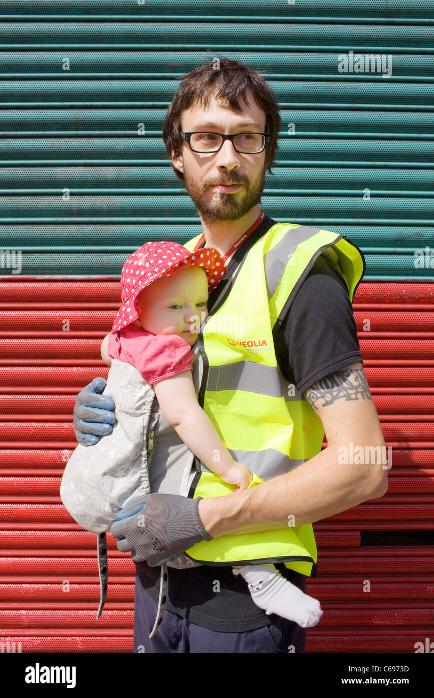 Ein Mann in einer Warnschutz-Jacke mit einem Baby. Stockfoto