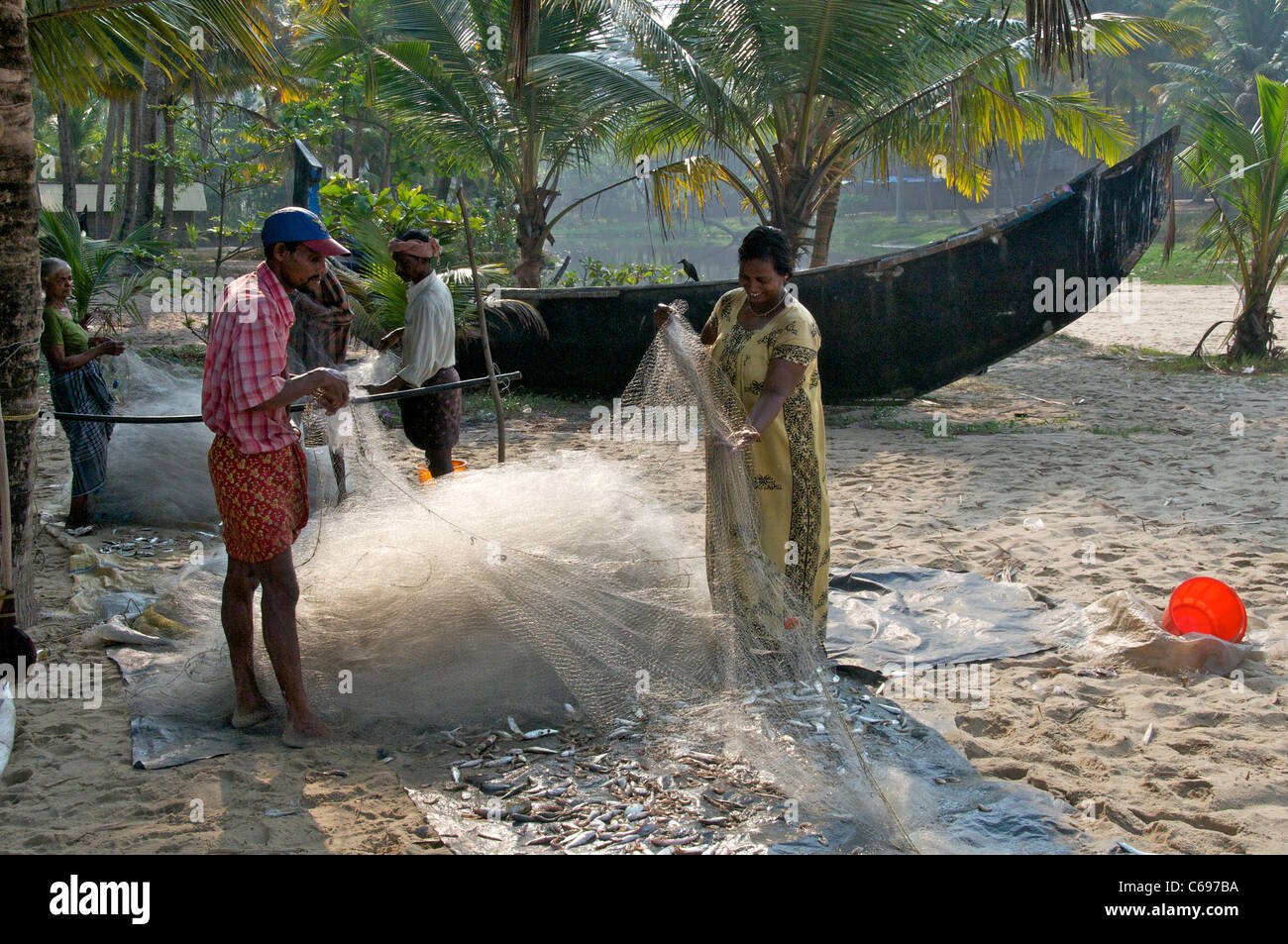 Familien, die Sortierung Fischernetze auf Marari Beach Kerala Süd-Indien Stockfoto