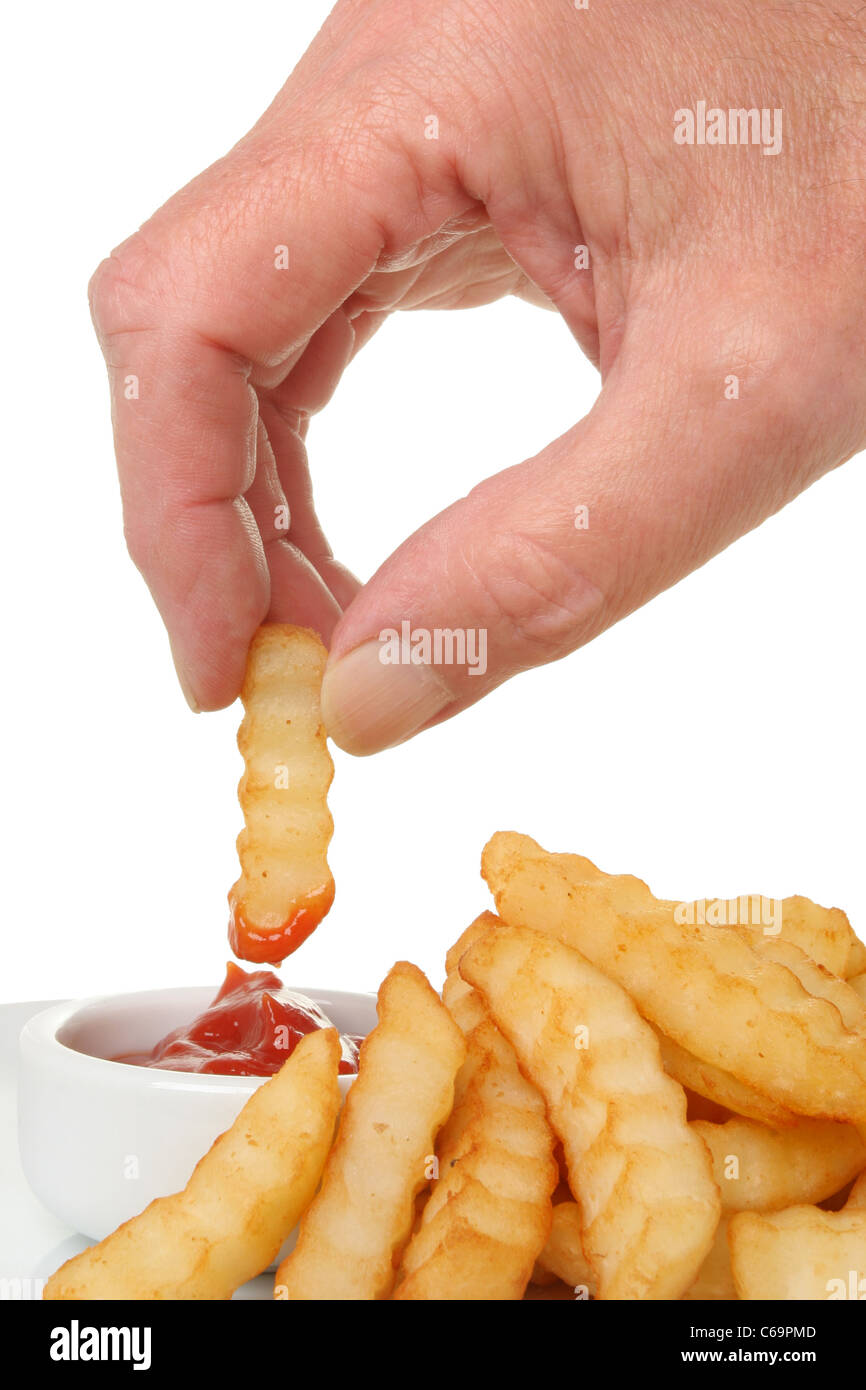 Nahaufnahme einer Hand eintauchen Pommes frites in Tomaten-ketchup Stockfoto