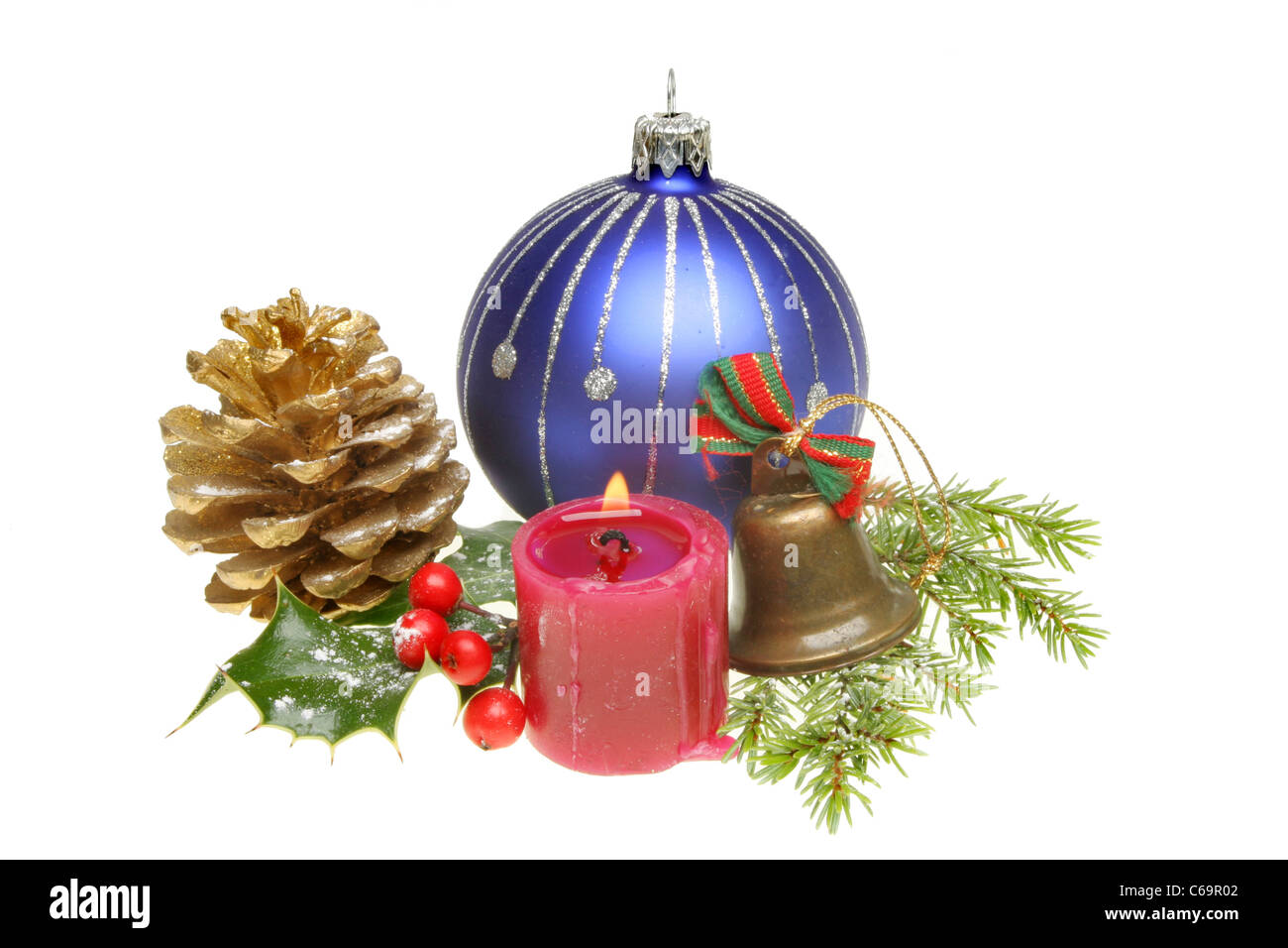 Weihnachtsschmuck und Schnee bestäubt saisonale Laub mit einer brennenden Kerze Stockfoto