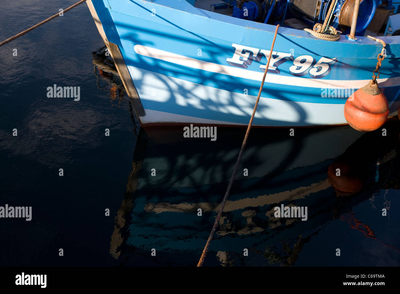 Die blaue-weiße Rumpf des FY95 Fischerboot in das Wasser am Plymouth Sutton Harbour, Barbican, wider. Stockfoto