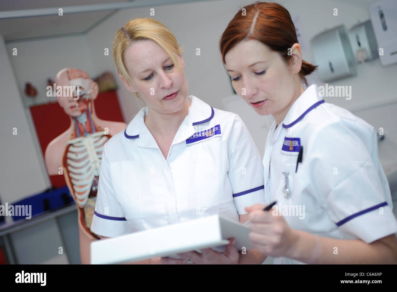 Schüler, die Krankenschwestern lesen Patientenakte durch menschliche Anatomie Modell in clinical Skills Lab Krankenhaus Krankenpflege Stockfoto
