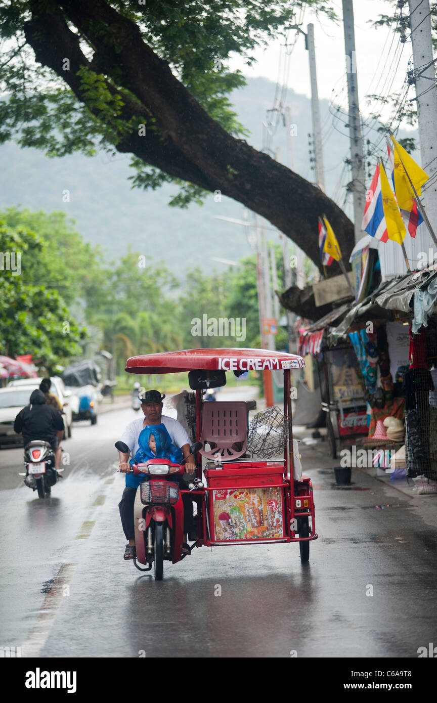 Eis Verkäufer mit einem Kind, einem motorisierten Dreirad im Regen Kanchanaburi Thailand Stockfoto