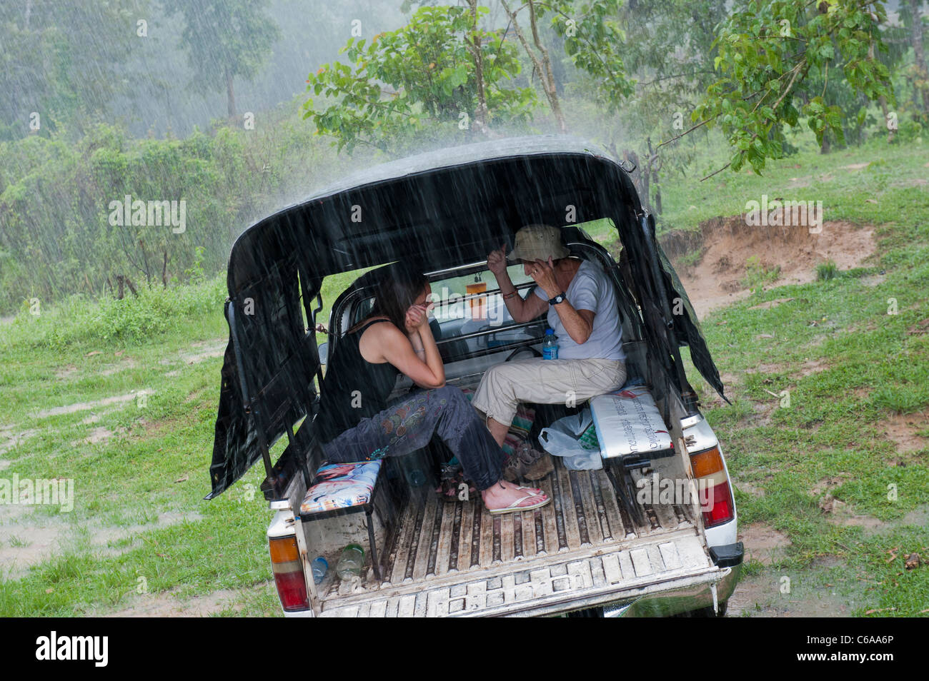 Zwei Frauen Zuflucht von Starkregen auf der Rückseite ein 4 x 4 Fahrzeug Thailand Asien Stockfoto