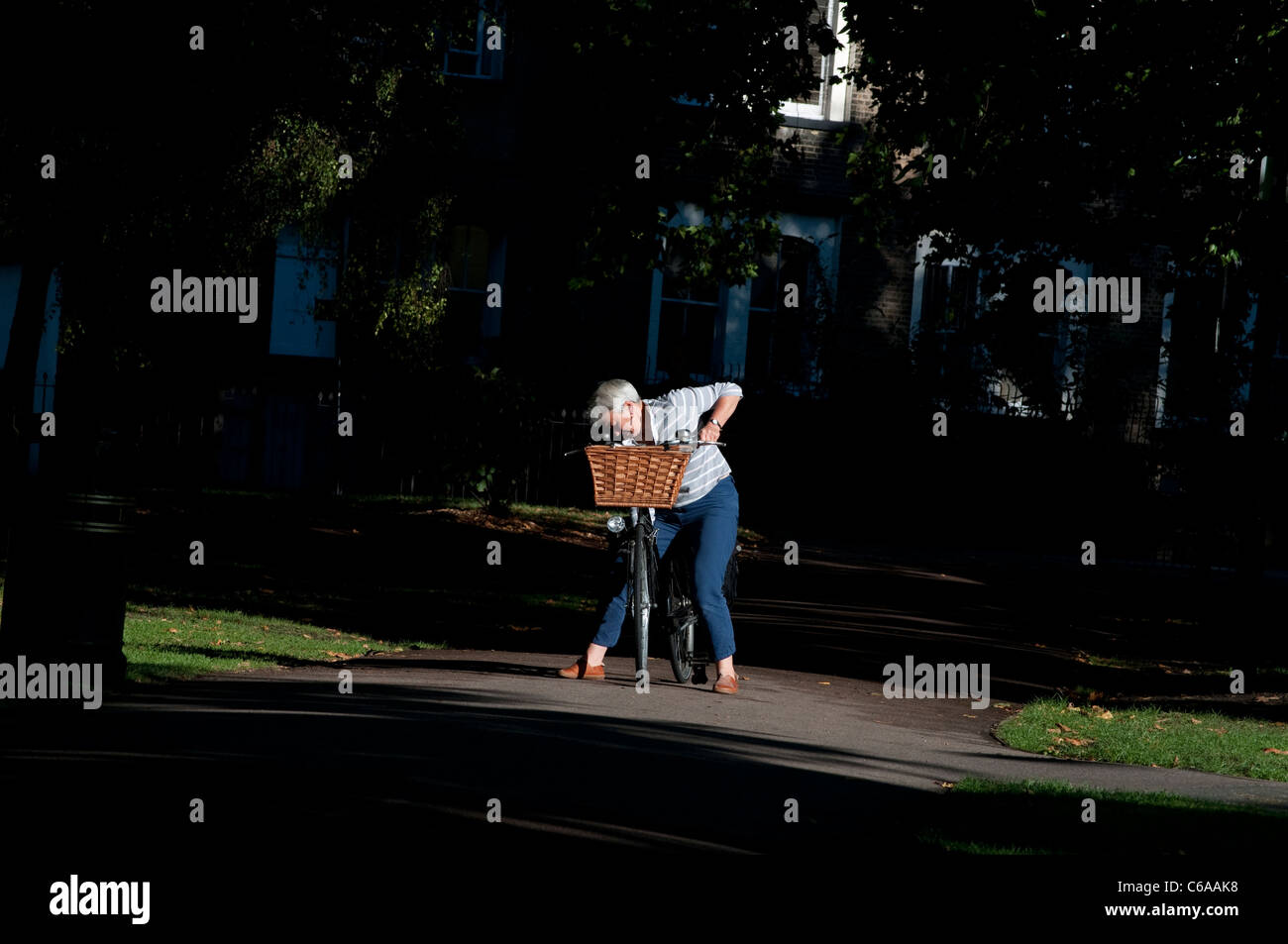 Ältere Frau, die ihr Fahrrad einstellen, London Fields Park, Hackney, London, UK Stockfoto