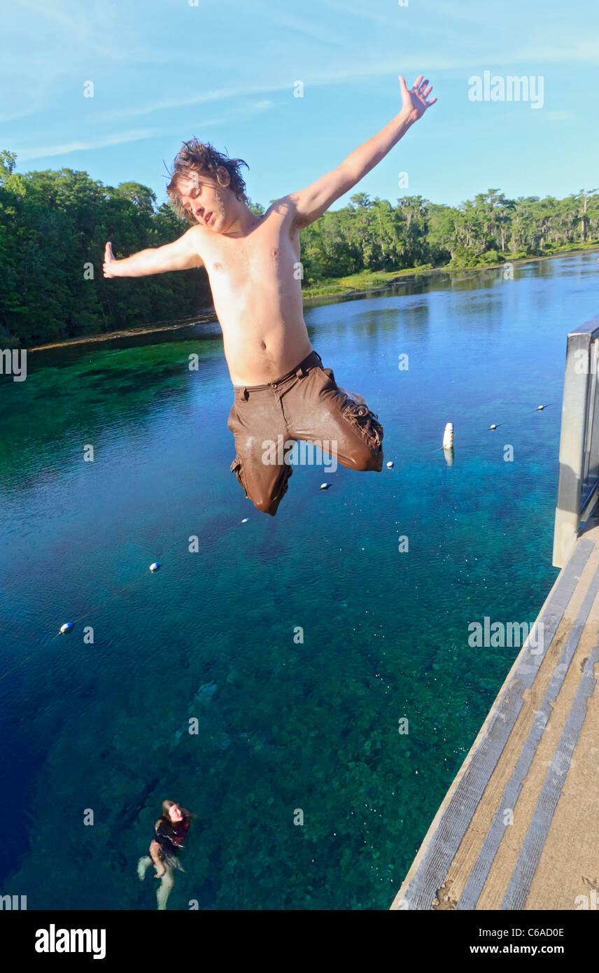Junger Mann springt in Wakulla Frühling von hohen Plattform, während seine Freundin schaut Stockfoto