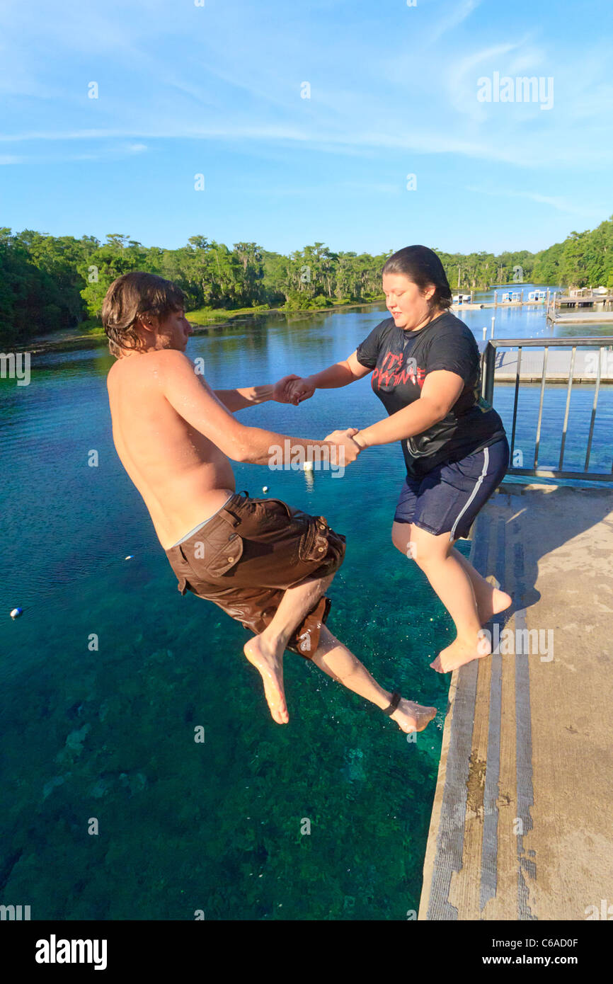 Junger Mann und Frau an den Händen halten und in den Wakulla Frühling von hohen Plattform springen Stockfoto