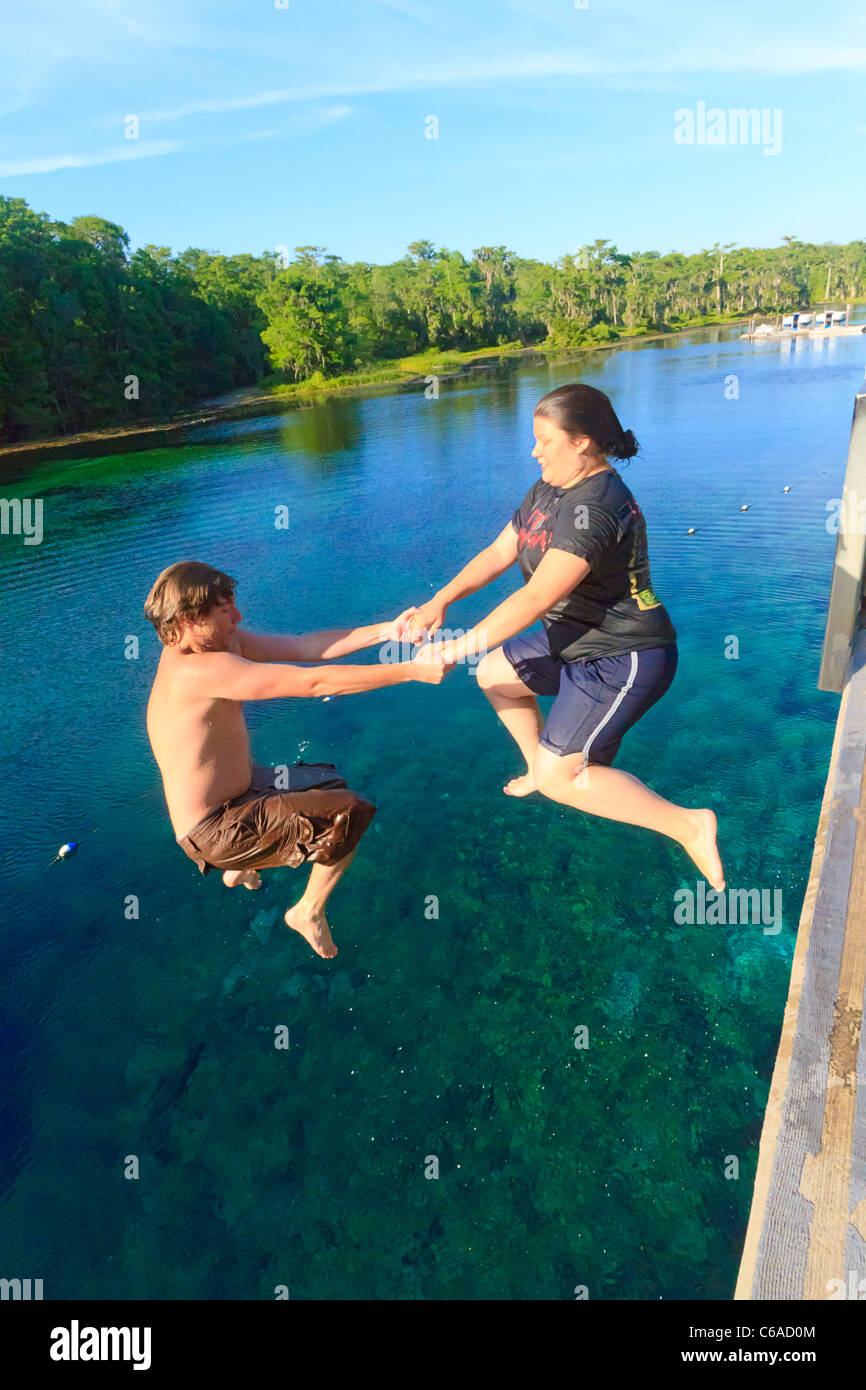 Junger Mann und Frau an den Händen halten und in den Wakulla Frühling von hohen Plattform springen Stockfoto