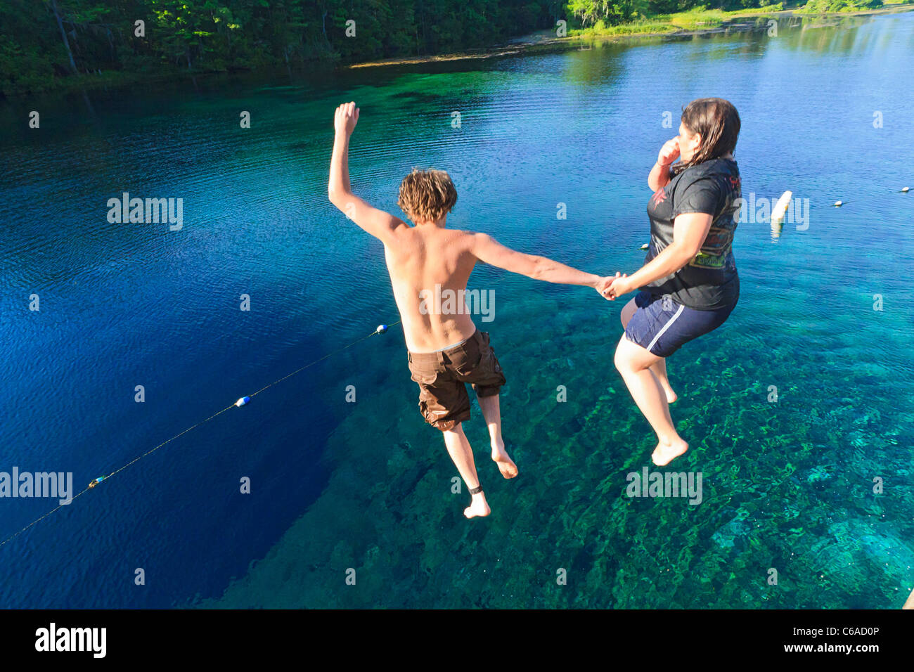 Junger Mann und Frau an den Händen halten und in den Wakulla Frühling von hohen Plattform springen Stockfoto