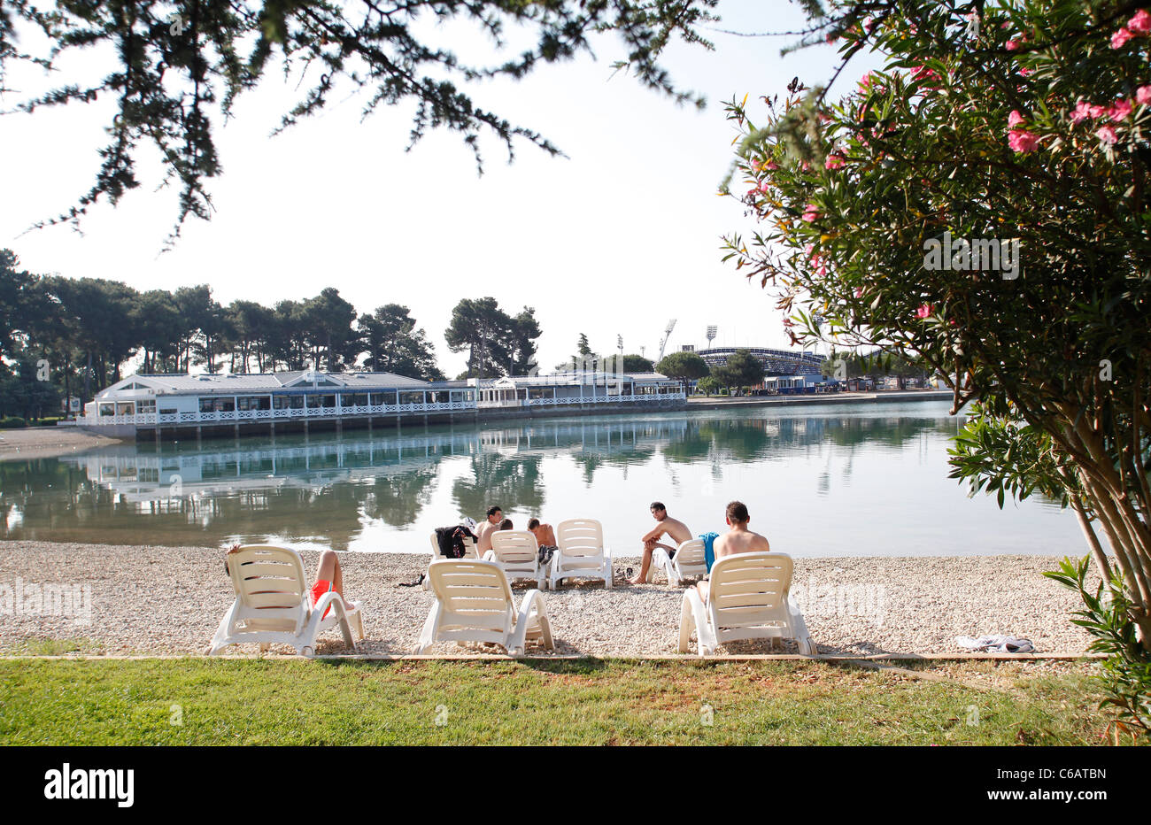 Touristen in Liegestühlen an der Lagune in Umag, Kroatien. Stockfoto