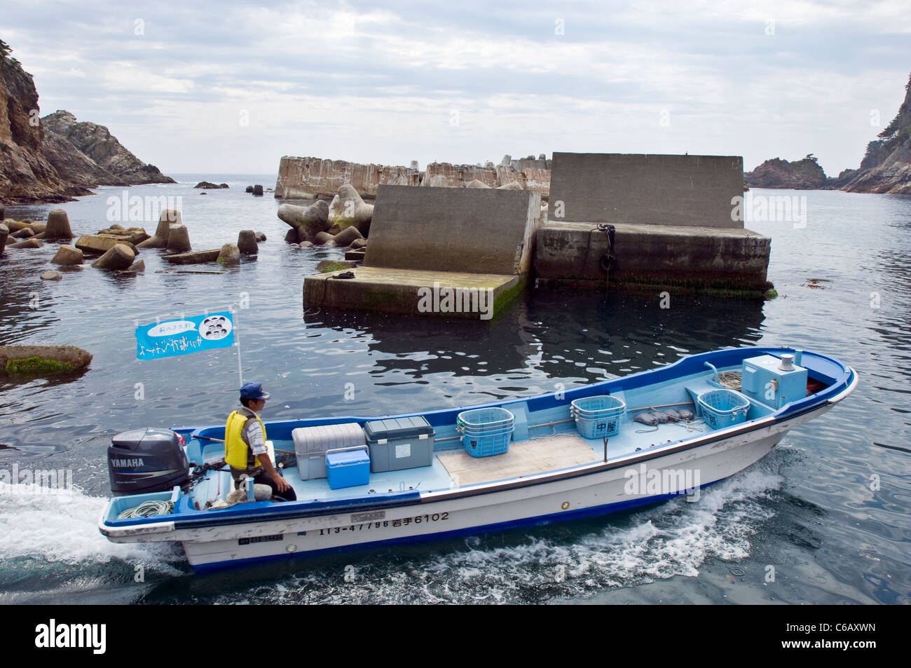 Ein Fischer navigiert aus einem schlecht Tsunami beschädigt Fischerhafen in Iwate Stockfoto
