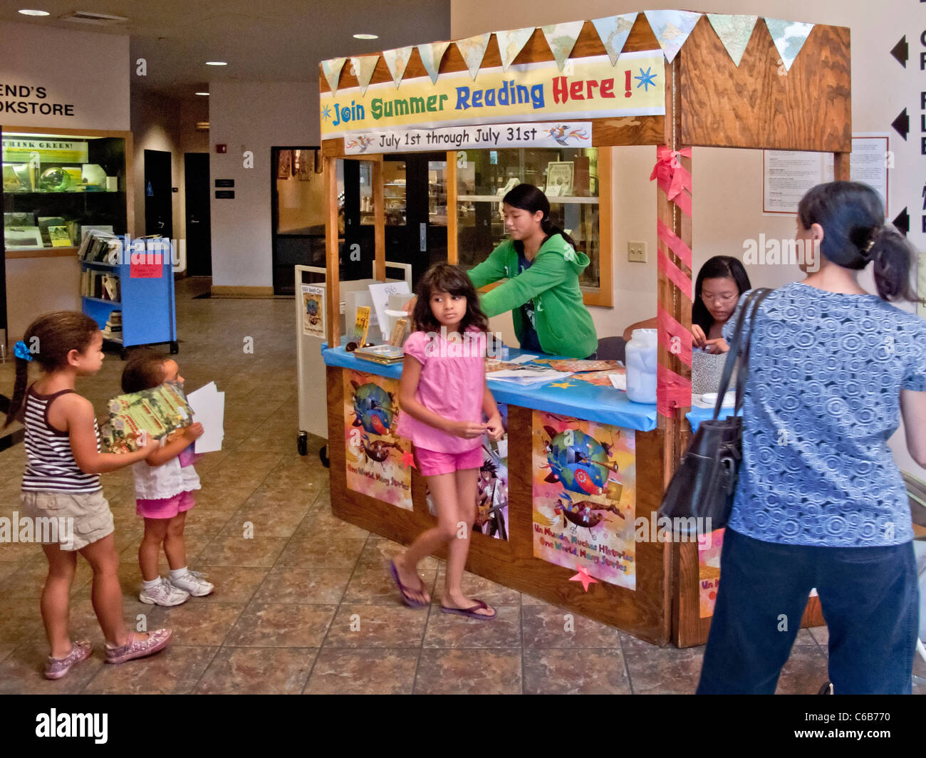Asiatisch-amerikanische Freiwillige beraten Sommer Lesung lateinamerikanische und asiatische Kinder in einer öffentlichen Bibliothek in Aliso Viejo, CA. Stockfoto