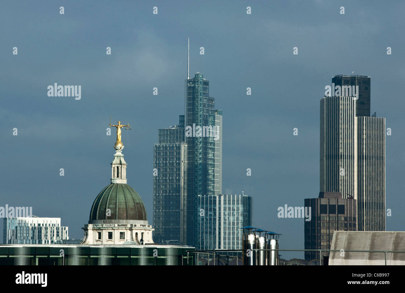 Justitia steht hoch oben auf dem Old Bailey Justizpalast mit der City of London im Hintergrund. London, UK. Stockfoto