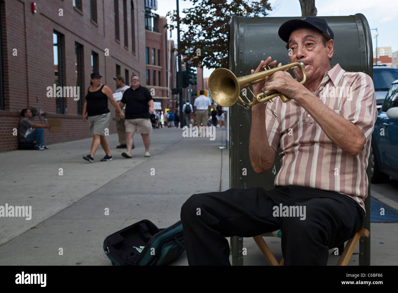 Denver, Colorado - ein Straßenmusikant spielt die Trompete für Tipps wie Coors Field für ein Baseball-Spiel Fans ankommen. Stockfoto