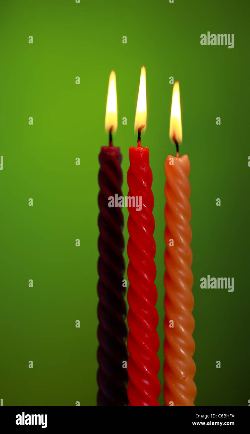 drei verdreht brennende Kerzen auf grünem Hintergrund Stockfoto