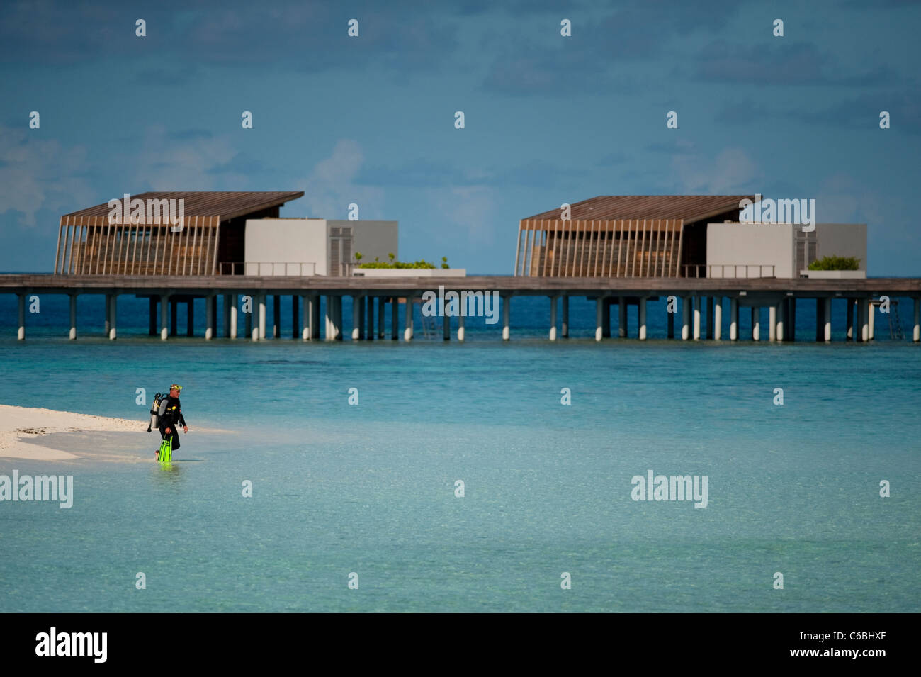 Taucher machen den Tauchgang, Chalets im Hintergrund, Alila Villas Hadahaa, Nord-Huvadhoo-Atoll, Malediven Stockfoto