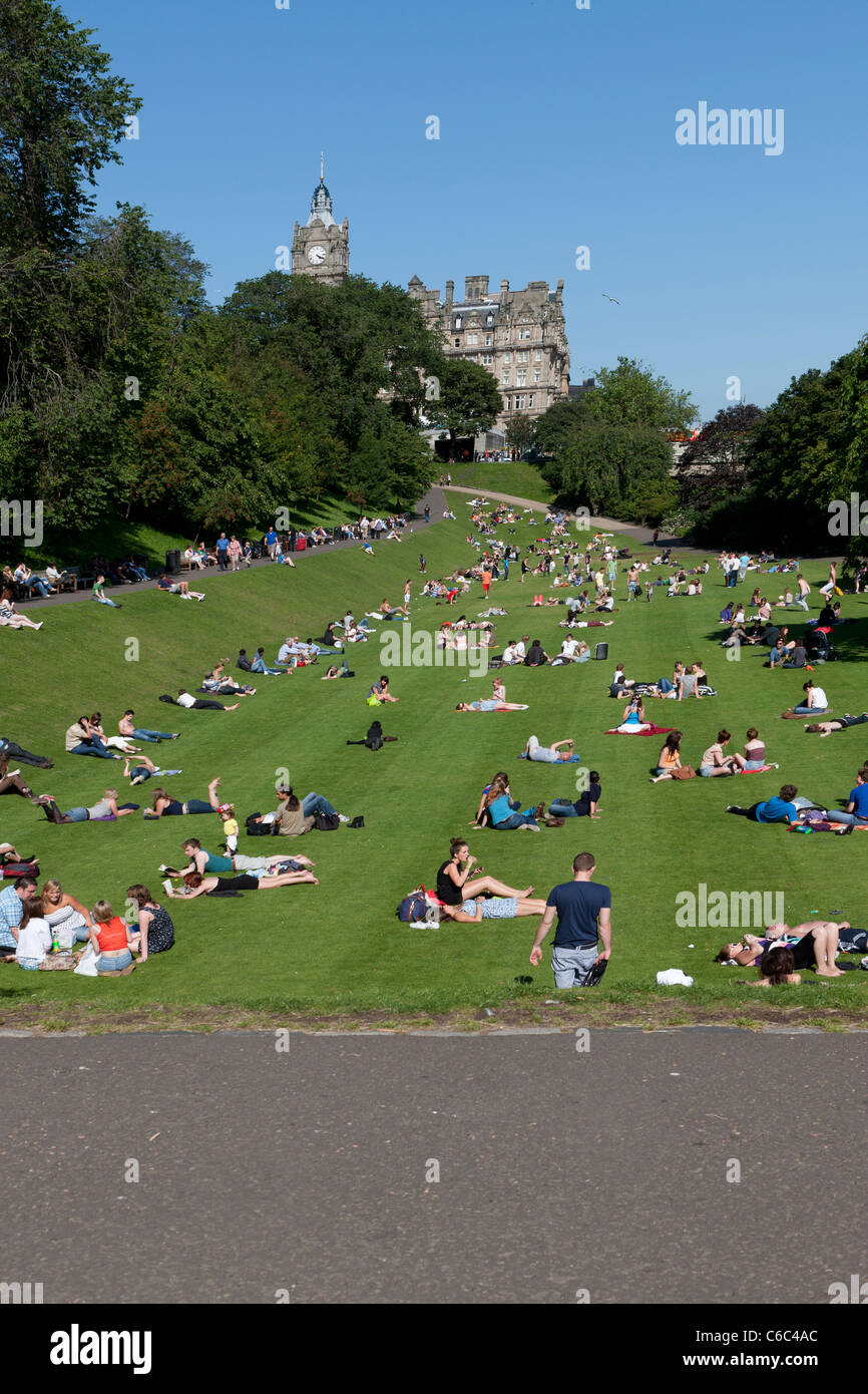 Princes Street Gardens-Edinburgh mit Menschen Sonnen Festlegung auf dem Rasen mit blauem Himmel an einem sonnigen Tag in Schottland Stockfoto