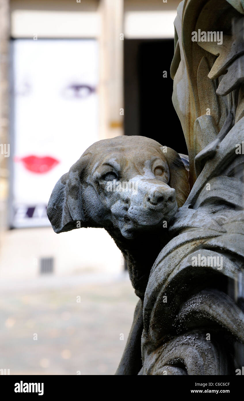 Gent/Gent, Belgien. Detail der Hund an der Basis des Brunnens - Werbung Plakat im Gesicht der Frau hinter Stockfoto