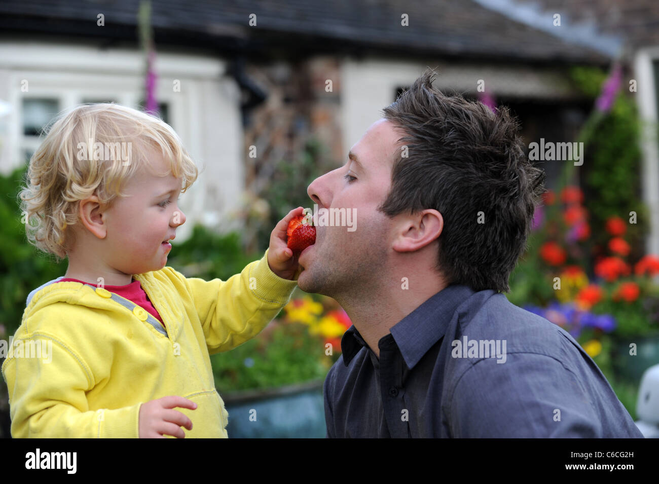 Junge und Mann teilen eine Erdbeere Stockfoto