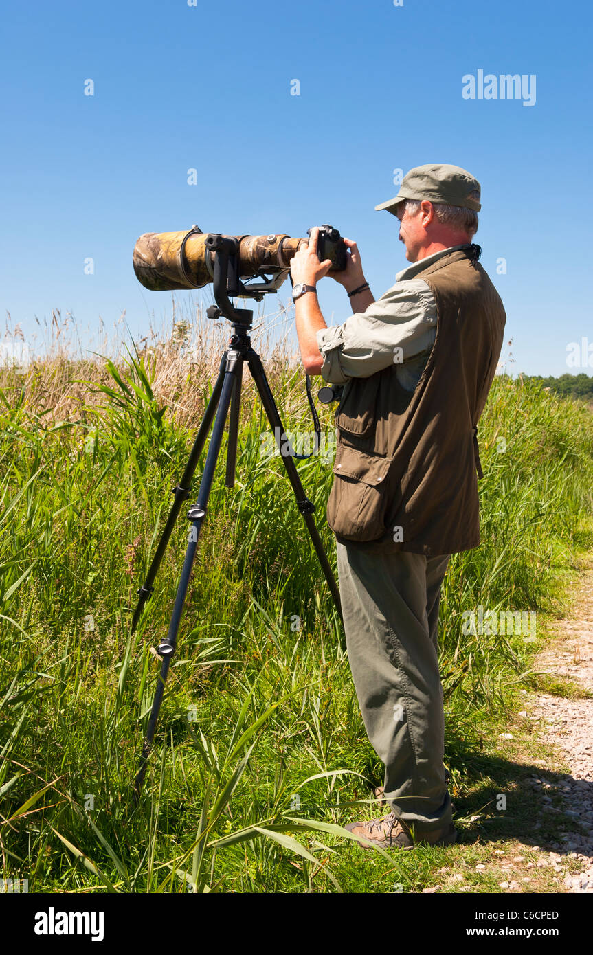 Ein Vogelfotograf mit einer Kamera mit einem großen Objektiv auf ein Stativ zu Minsmere Vogel zu reservieren, Suffolk, England, Großbritannien, Vereinigtes Königreich Stockfoto