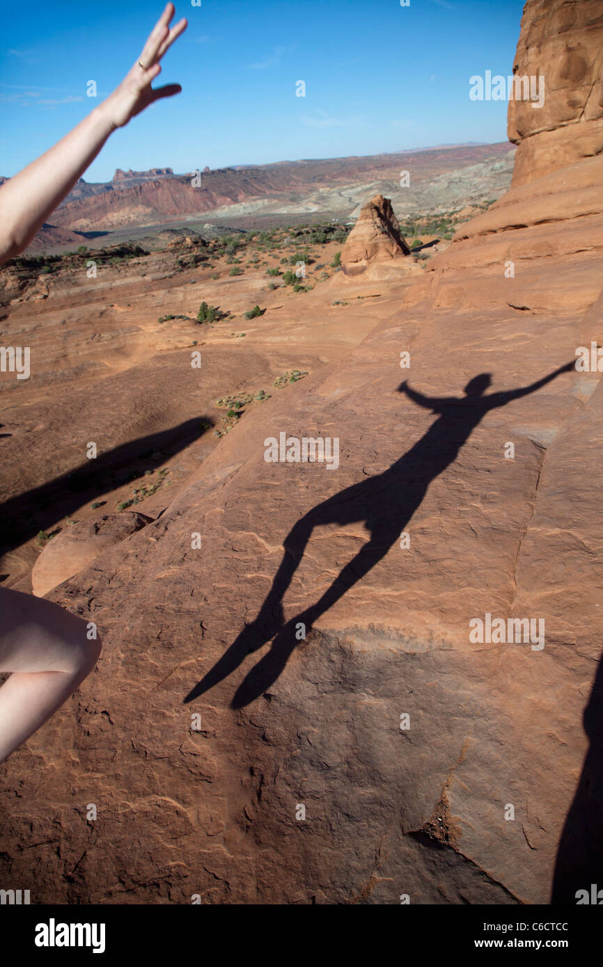 Moab, Utah - eine junge Frau tanzt mit ihrem Schatten auf Slickrock im Arches National Park. Stockfoto