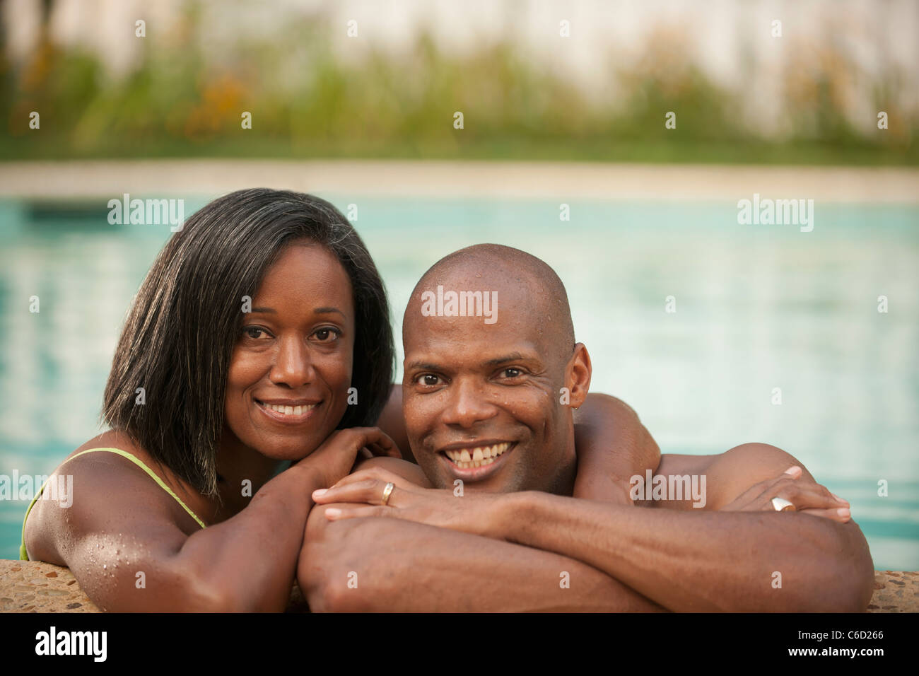 Afrikanische amerikanische paar stützte sich auf den Rand des Schwimmbad Stockfoto