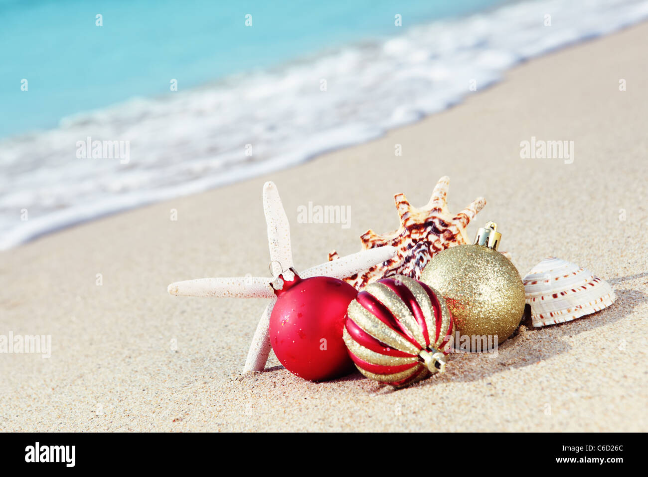 Weihnachtskugeln und Muscheln am Strand nahe dem Meer. Stockfoto