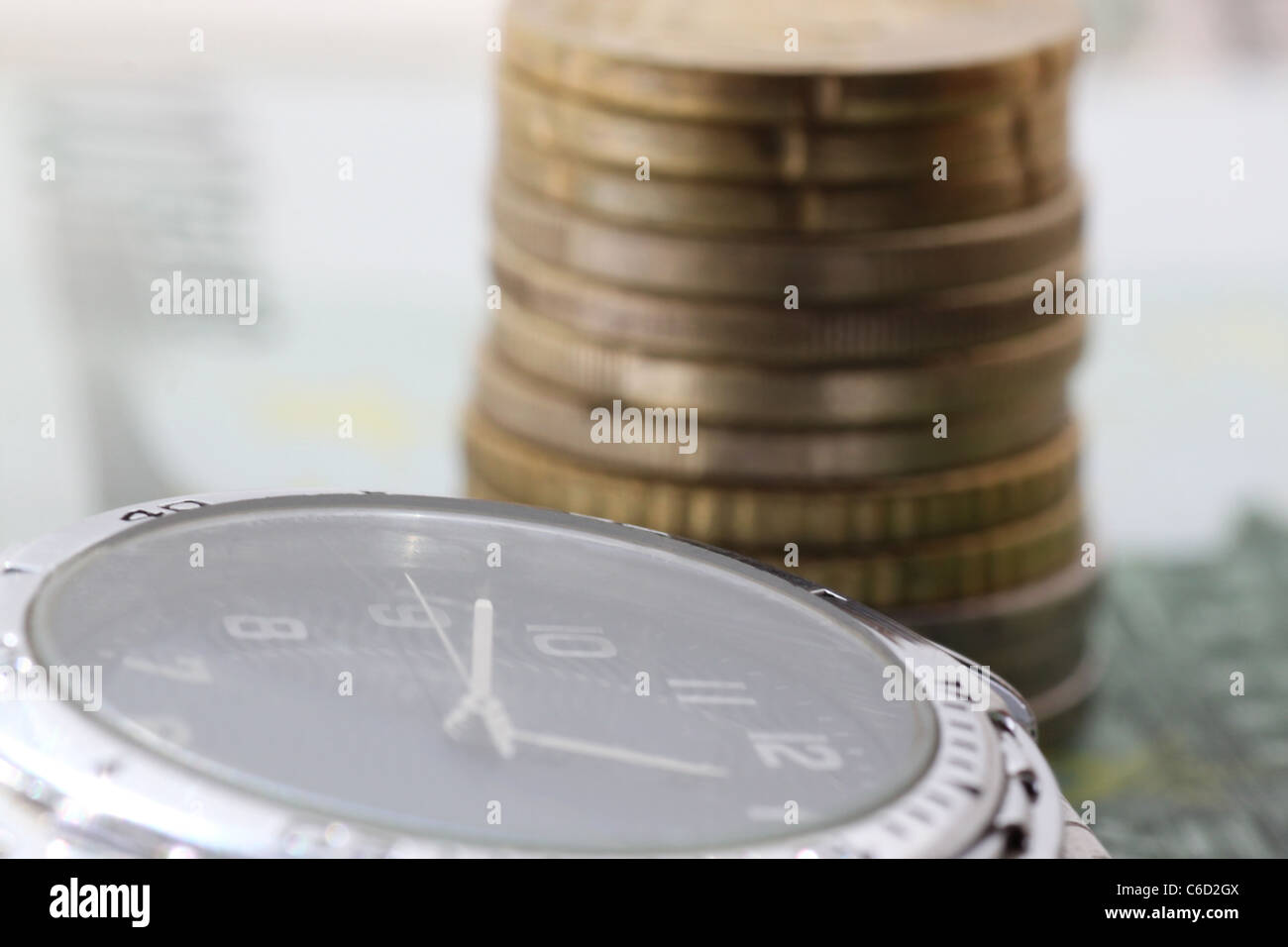 Zeit ist Geld - Uhr vor Haufen von Euro-Münzen Stockfoto