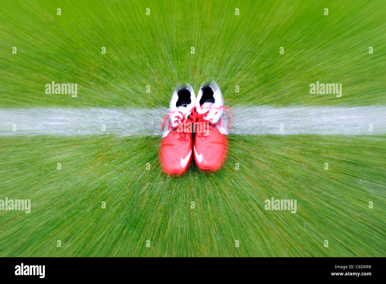 Verschwommene paar rote Nike Fußballschuhe auf die weiße Linie eines Fußballfeldes. Stockfoto