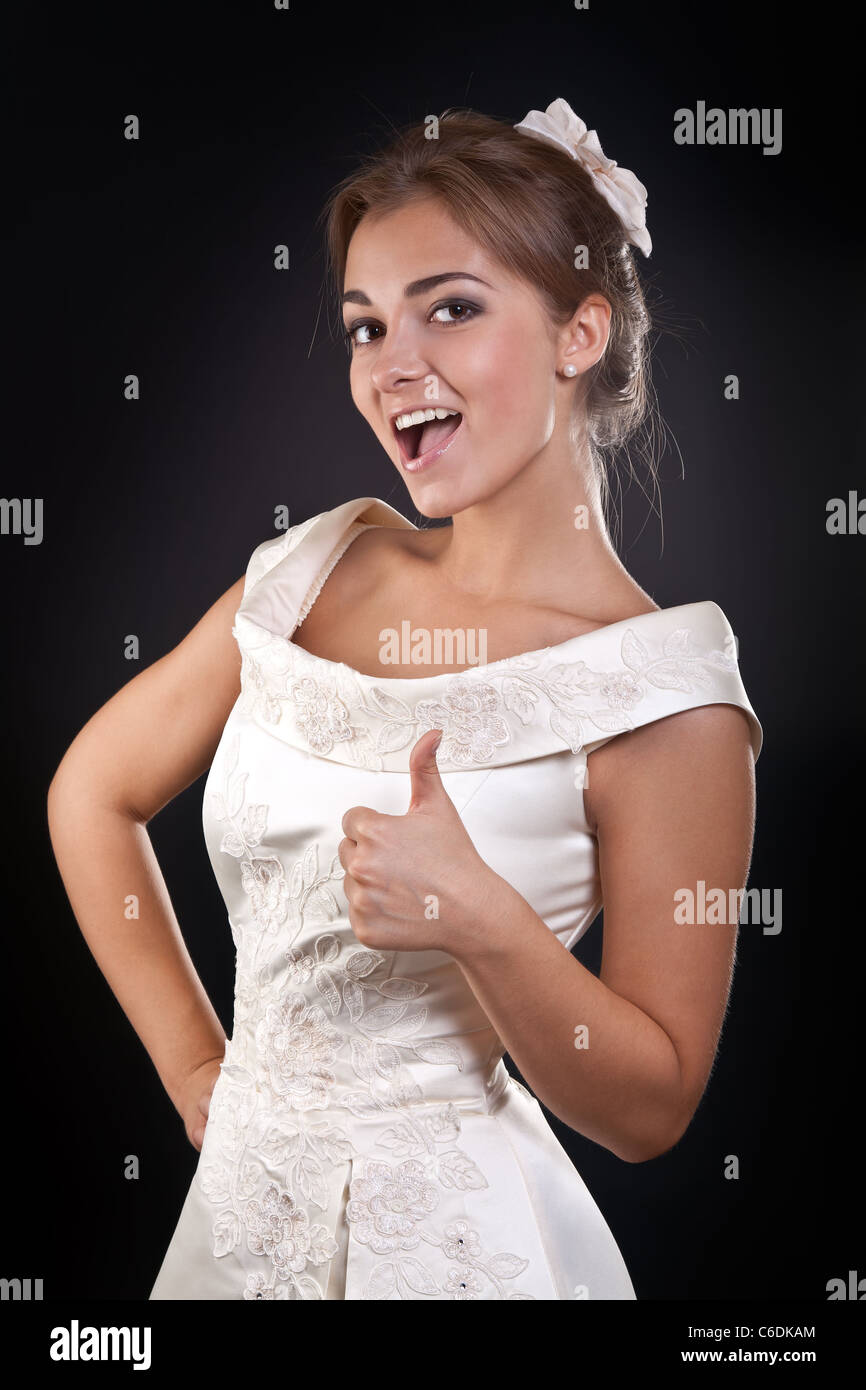Schönes Mädchen in Tracht zeigt "OK" im Studio auf einem schwarzen Hintergrund Stockfoto