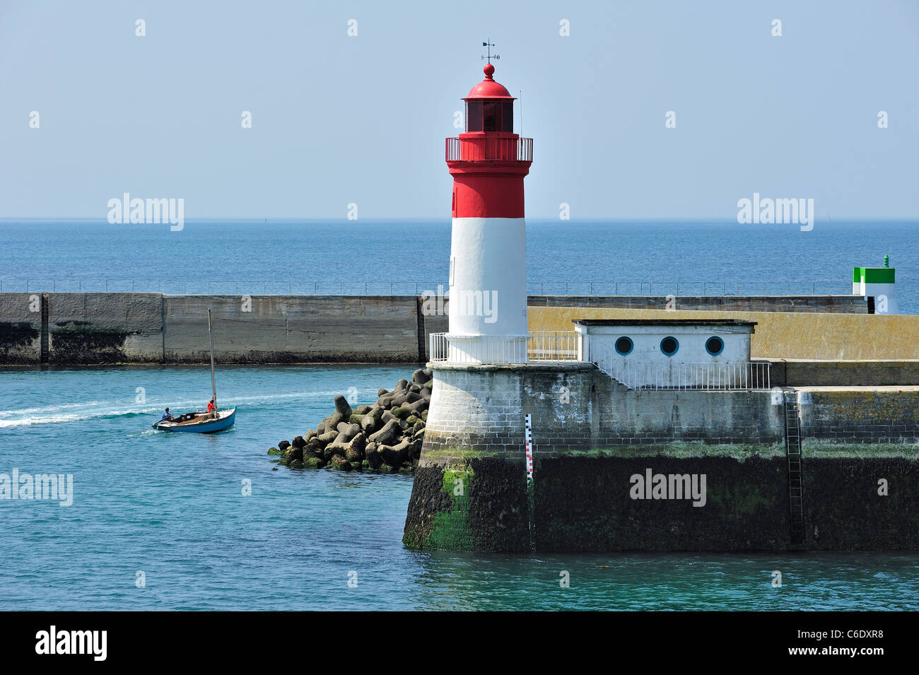 Leuchtturm und Segelboot verlassen des Hafens Guilvinec, Bretagne, Frankreich Stockfoto
