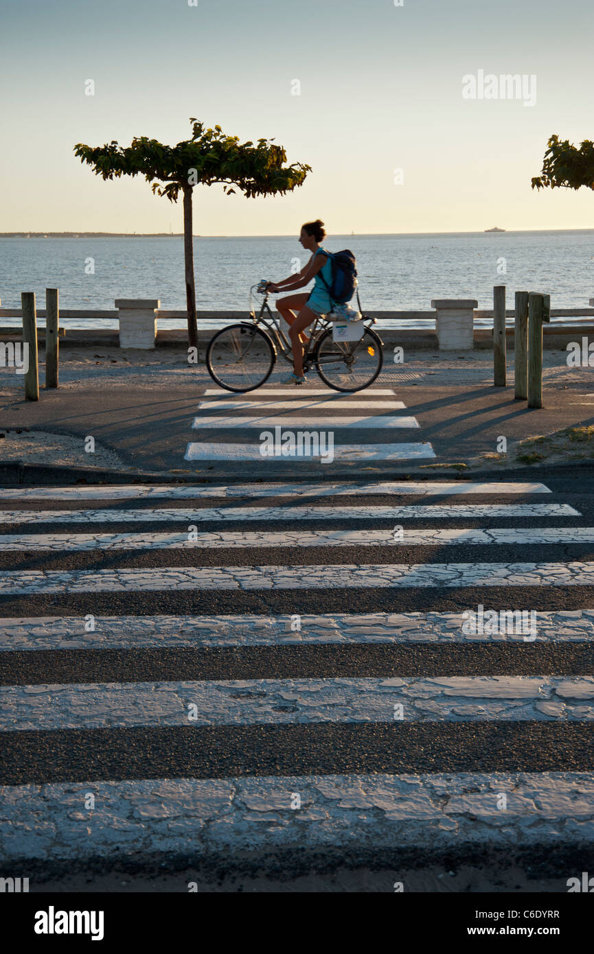 Der Strand bei Saint Georges De Didonne, Charente-Maritime, Frankreich.  Radfahrer fährt entlang der Strandpromenade in der Nähe von einem Zebrastreifen Stockfoto