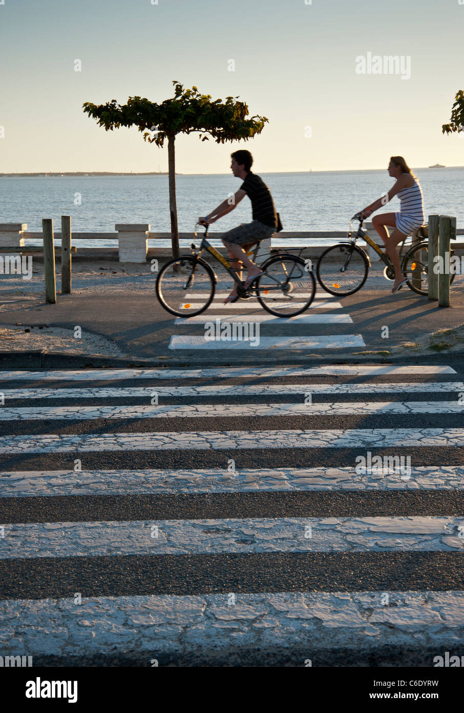 Der Strand bei Saint Georges De Didonne, Charente-Maritime, Frankreich. Radfahrer fahren entlang der Strandpromenade in der Nähe von einem Zebrastreifen Stockfoto