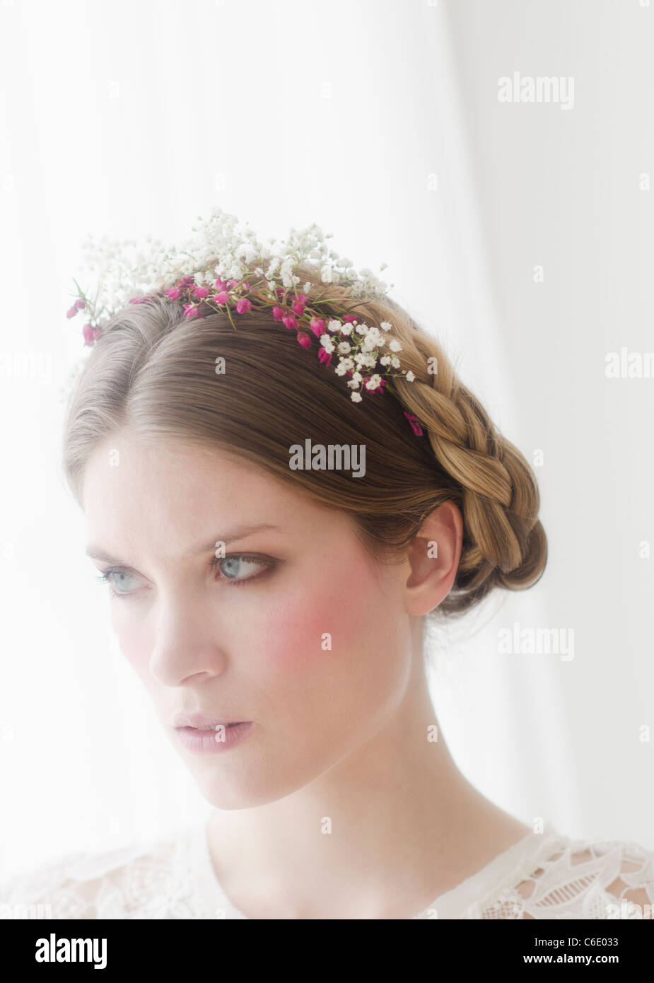 Nachdenkliche junge Frau mit Blumen im Haar Stockfoto