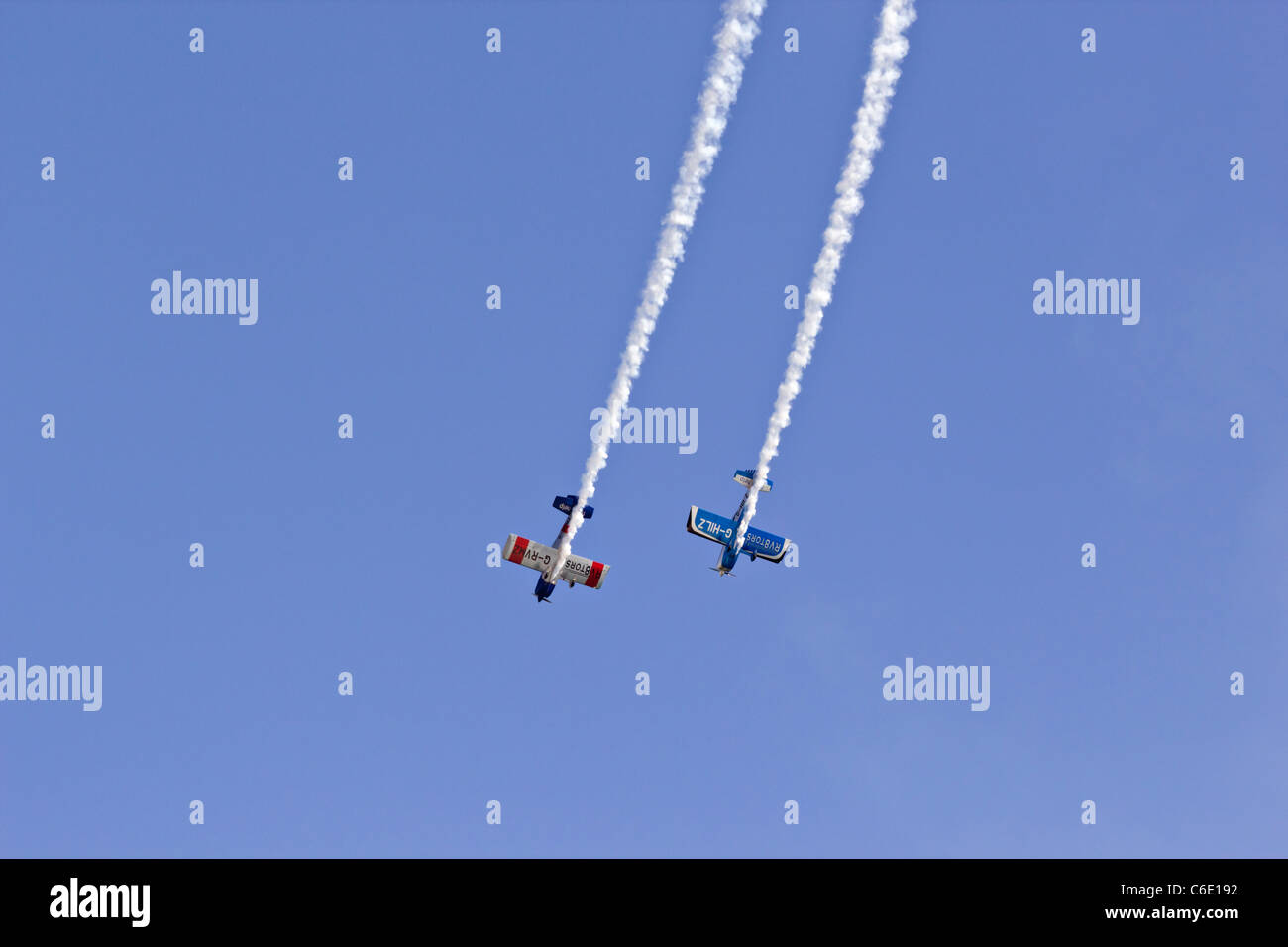 Zwei stunt Flugzeuge tauchen in engen Formation mit Rauch Trails im klaren, blauen Himmel fliegen Vans RV-8 G-HILZ und G-RVMZ Stockfoto