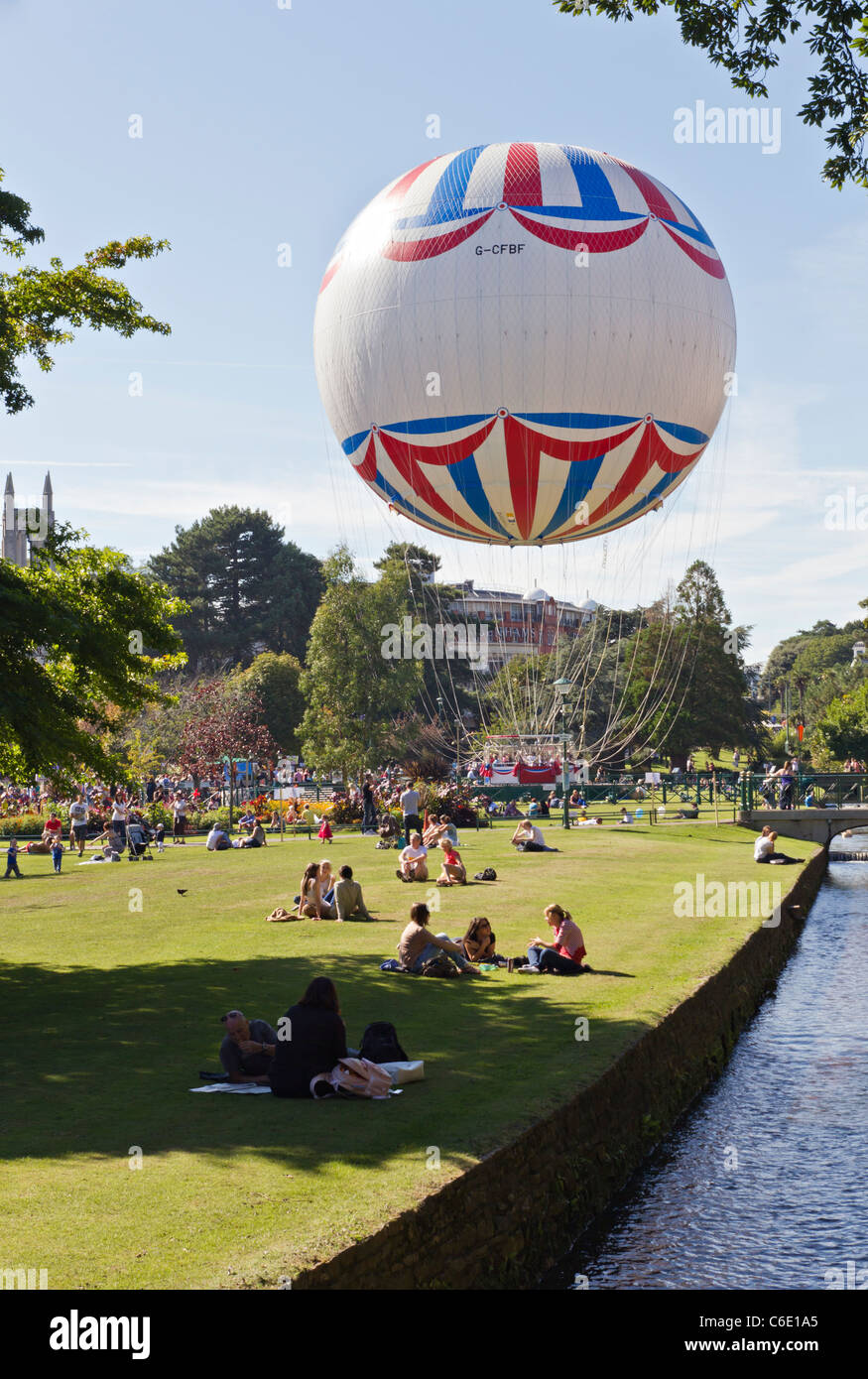 Neue Bournemouth Auge Beobachtung Heliumballon an schönen sonnigen Tag mit Menschen entspannen im Garten neben fließenden Wasser Stockfoto