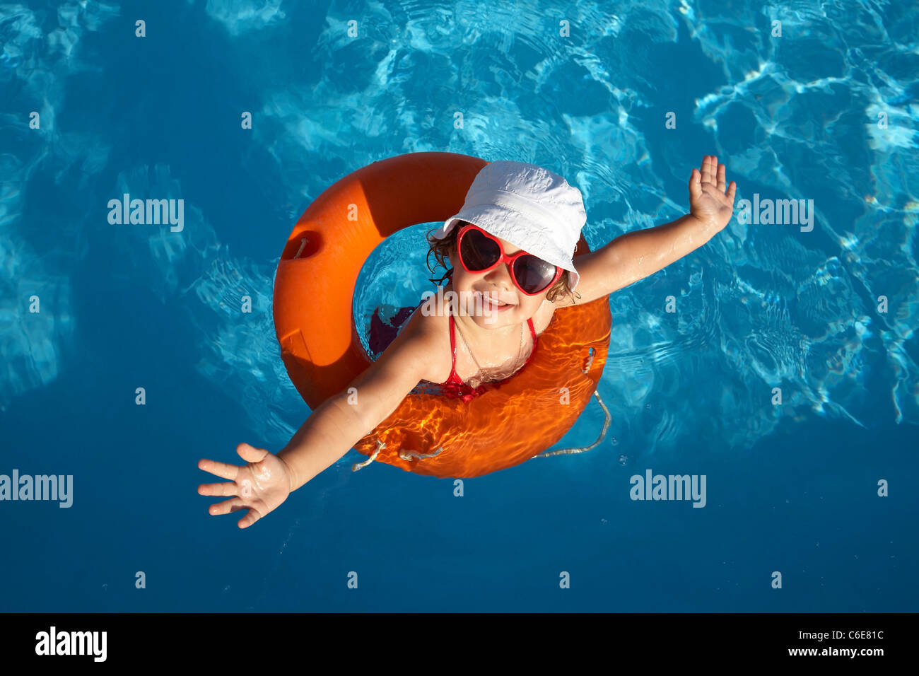 Lustige kleine Mädchen schwimmt in einem Pool in eine orange Rettungsring Stockfoto