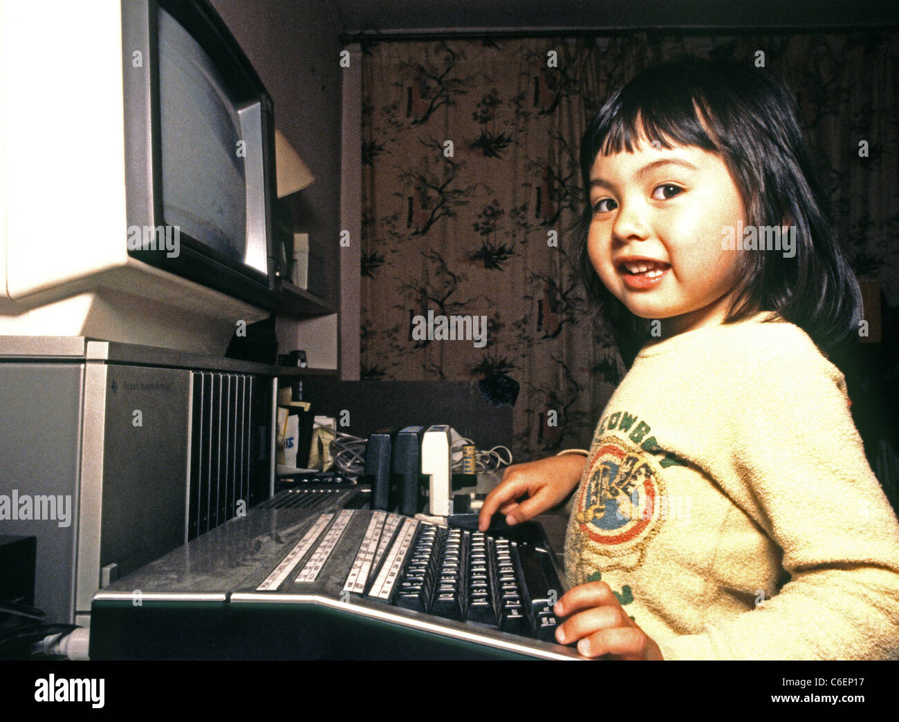 drei Jahre altes Mädchen spielt mit einem Heimcomputer TI 99 4a, 1986. Kalifornien, USA Stockfoto