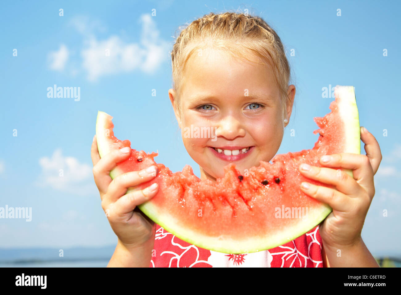 Porträt von niedlichen Mädchen mit Frieden rote Wassermelone auf blauen Himmelshintergrund Stockfoto