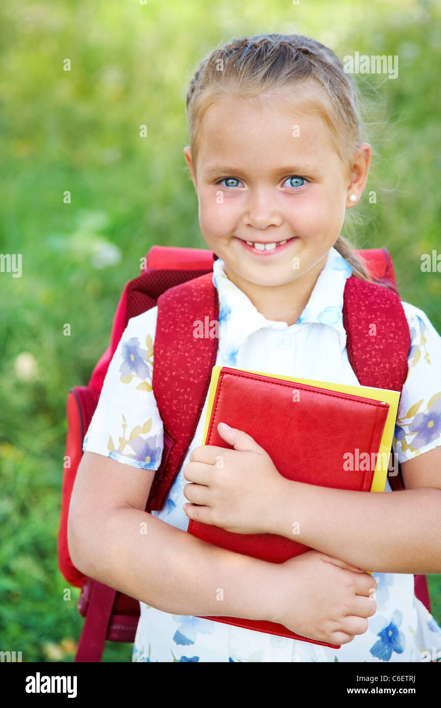 Porträt der niedliche Mädchen mit roten Rucksack und Bücher Stockfoto