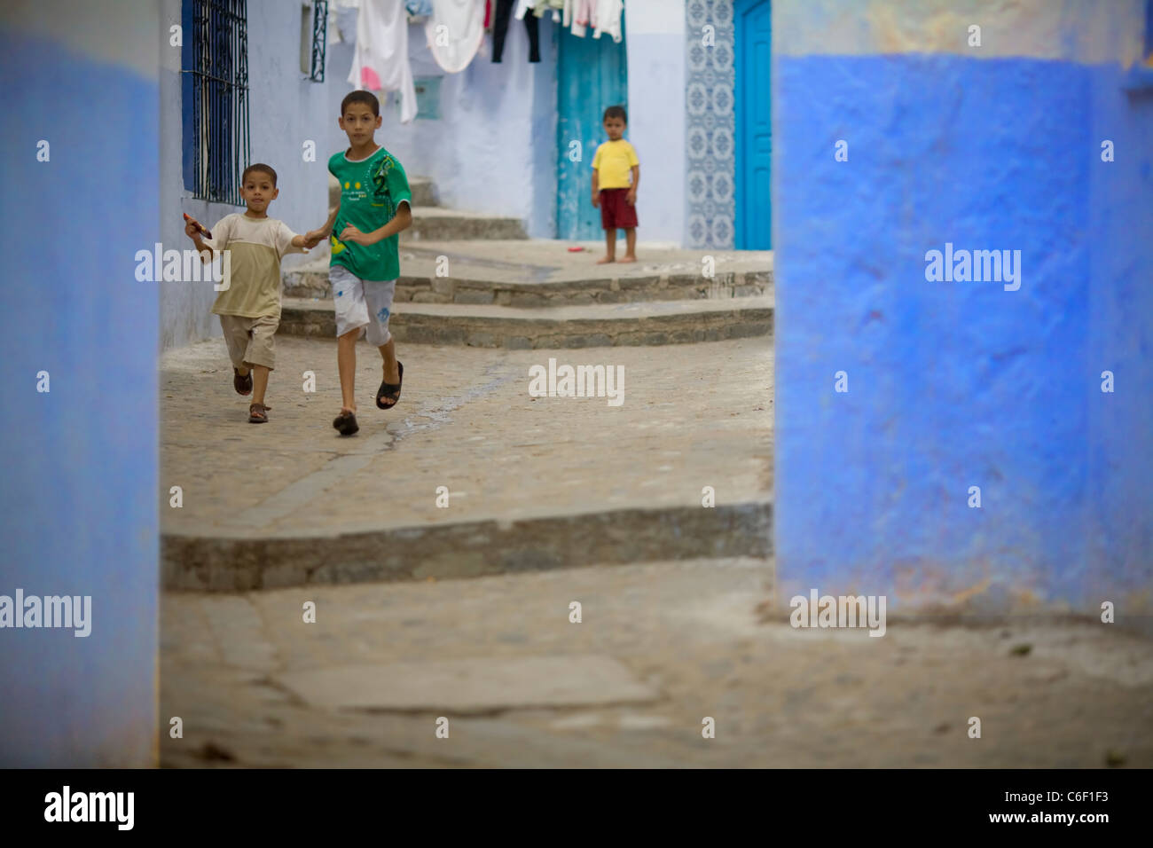 Kinder spielen unter den blauen Häuser und Gassen von Chefchaouen, Marokko Stockfoto