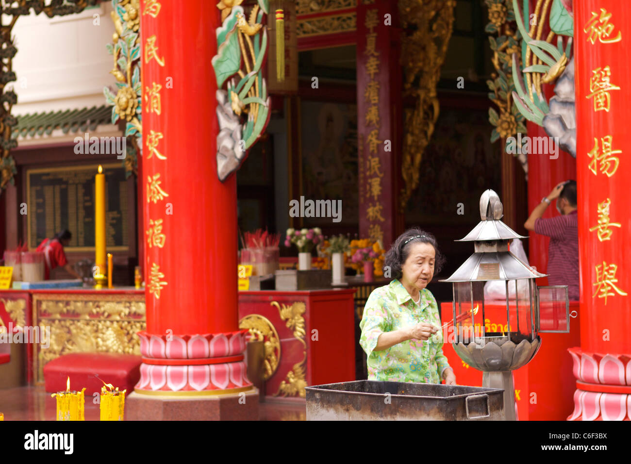 Eine Dame Lichter Weihrauch in einem bunten chinesischen Tempel in China Town im Samphanthawong Bezirk von Bangkok Stockfoto