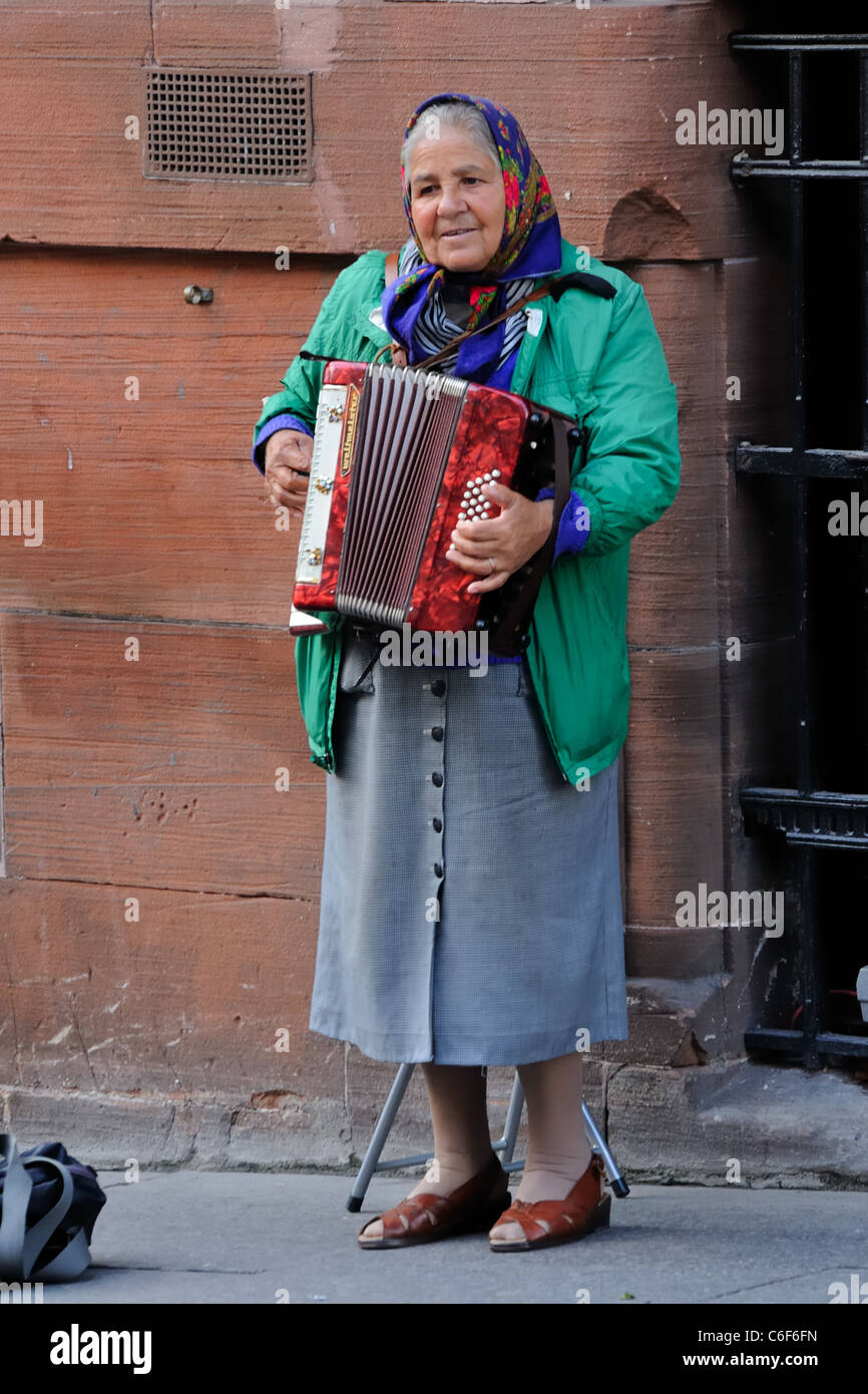 Alte Dame eingewanderte Gaukler spielen Akkordeon auf der Buchanan Street in Glasgow, Schottland, Großbritannien Stockfoto