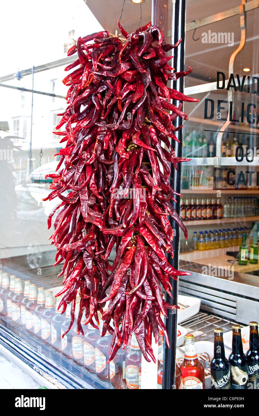 Rote Chilis hängen vor ein Feinkostgeschäft in Whitstable High Street, Kent Stockfoto